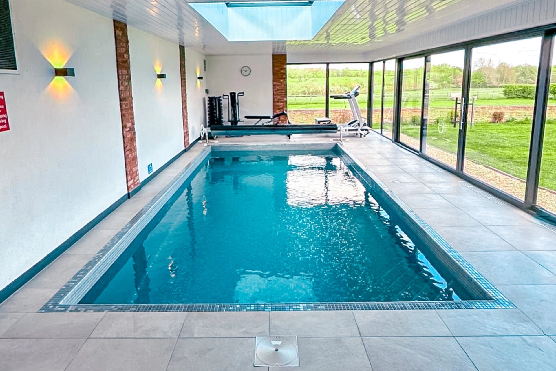 Indoor pool with large windows overlooking a garden
